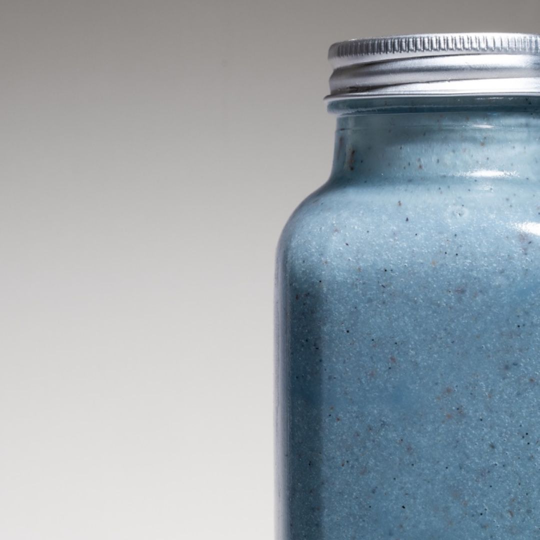 Close-up of a bright blue spirulina smoothie in a reusable to-go bottle, captured in a studio with a minimalistic, modern background.