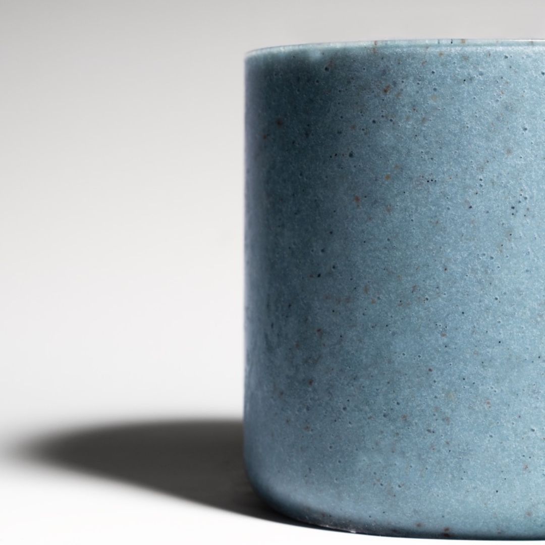 Close-up of a vibrant blue spirulina smoothie in a sleek, minimalistic glass, set in a clean studio setting with soft lighting.