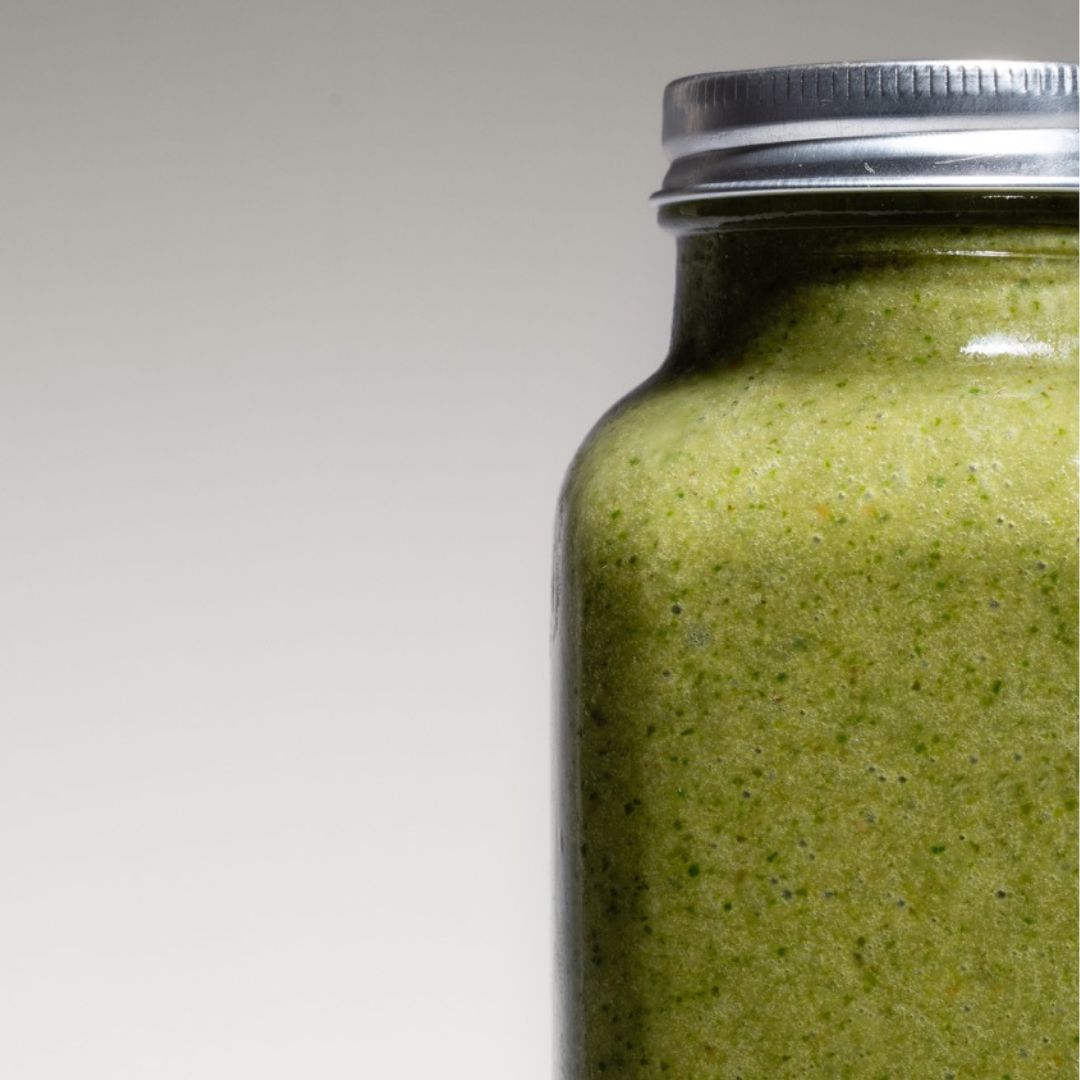 Close-up of a fresh green Nature’s Balance smoothie in a reusable to-go bottle, captured in a studio with a minimalistic, modern background.