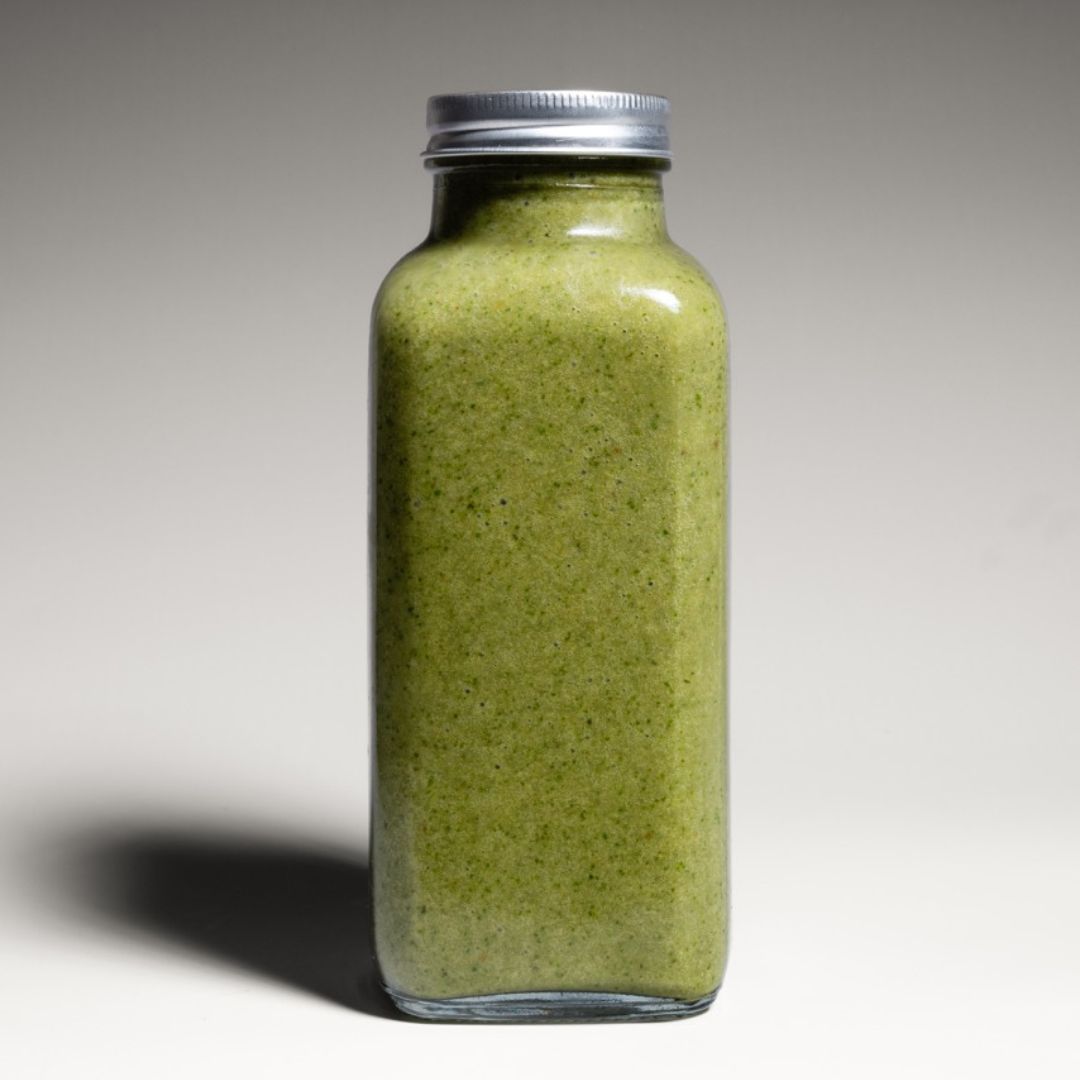 A fresh green Nature’s Balance smoothie in a reusable to-go bottle, photographed in a studio with a clean, minimalistic background and soft lighting.